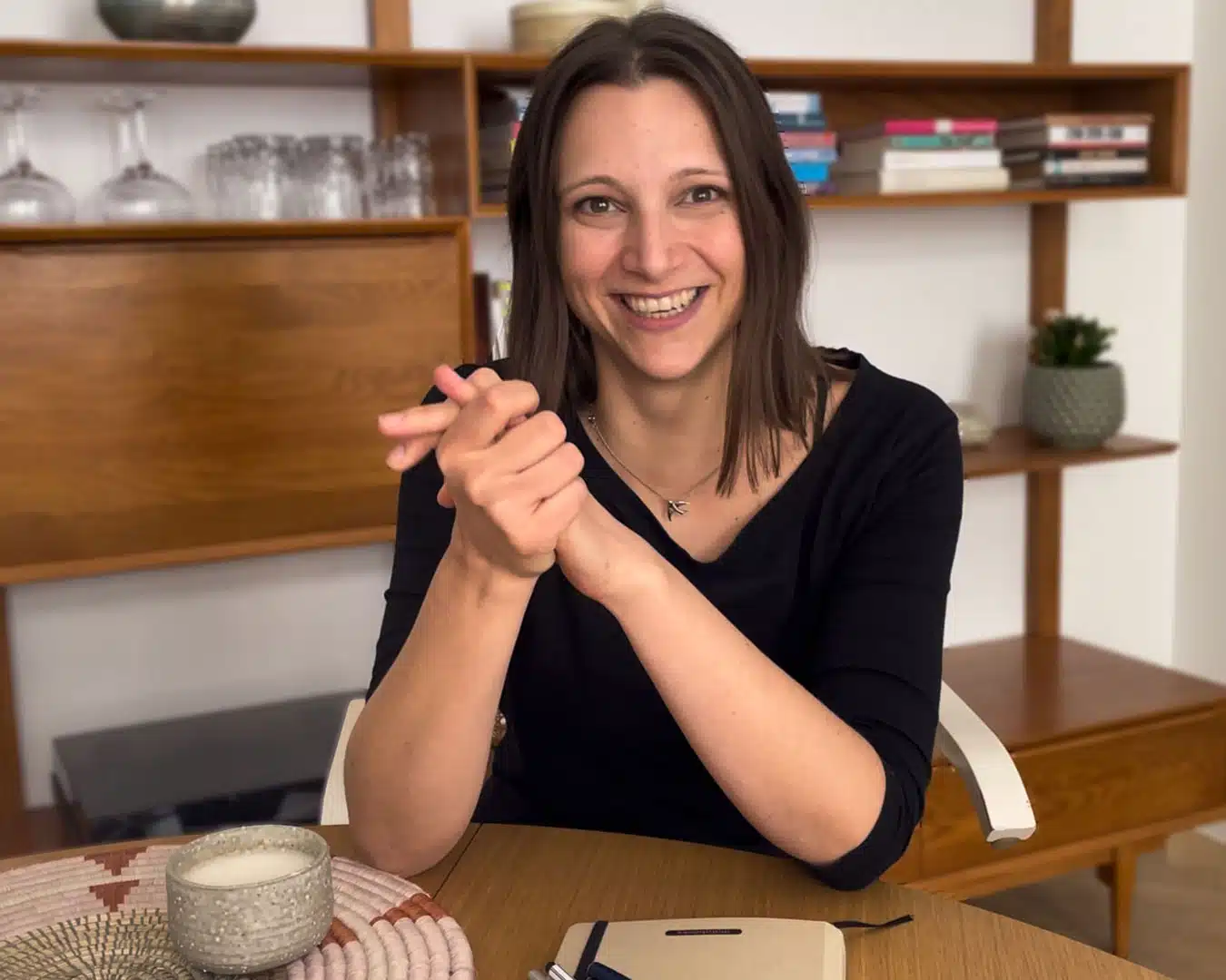 Portrait einer jungen lachenden Frau an einem Tisch mit einem Notizbuch und einer Tasse Kaffee