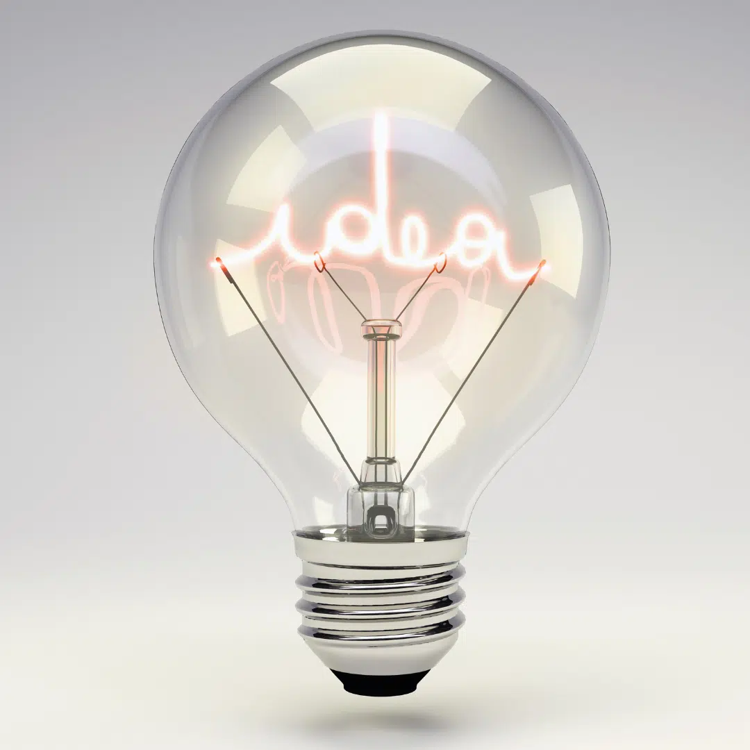 Eine Glühbirne, in der das Wort "Idea" leuchtet vor einem Hintergrund mit weiß-grauem Farbverlauf